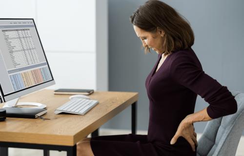ergonomie-vrouw-heeft-rugpijn-aan-bureau-door-slechte-zithouding